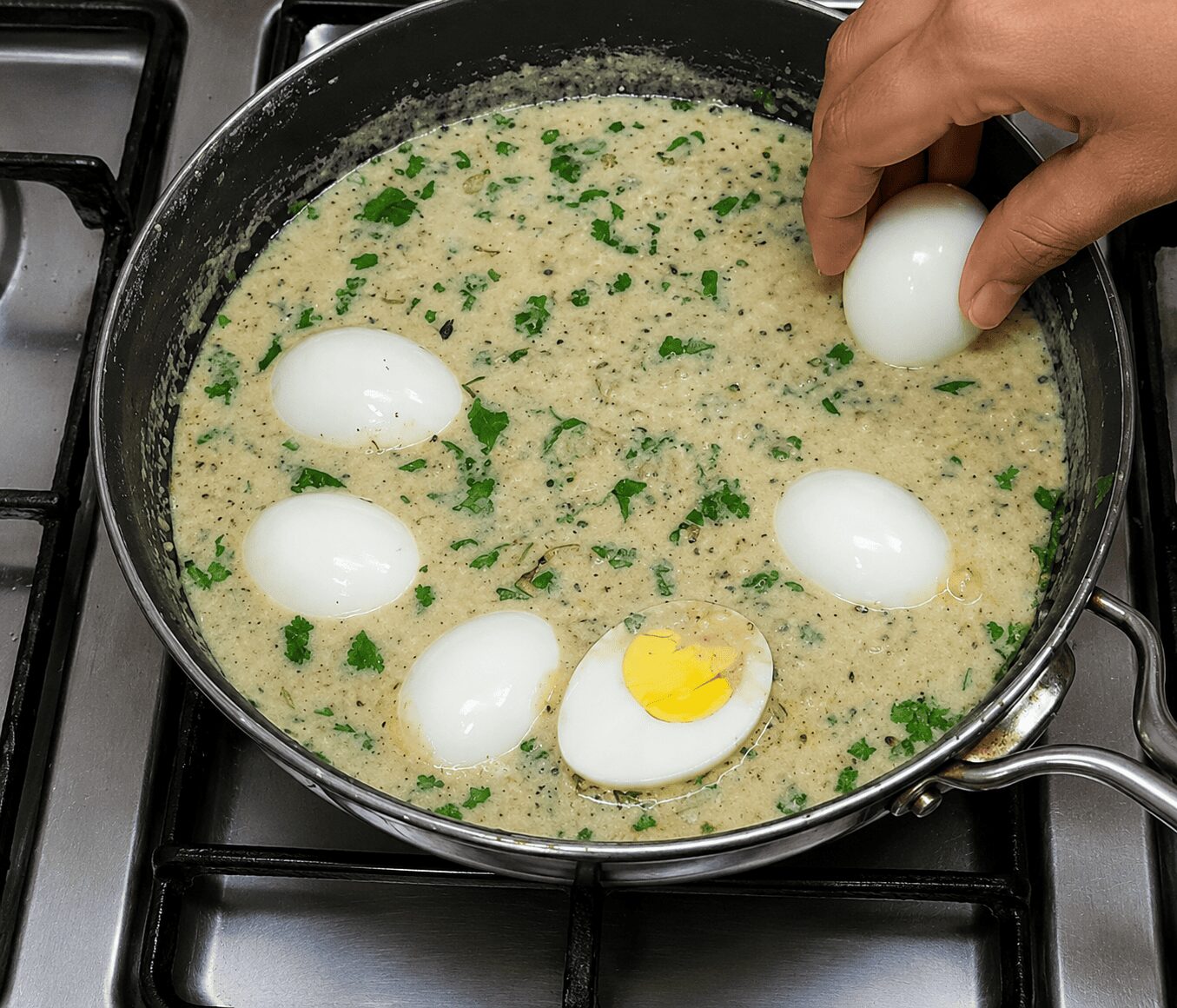 Halved boiled eggs placed yolk-down in the malai gravy