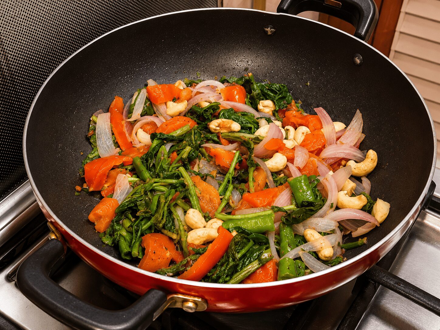 Spinach, onion, tomato, cashews, and green chilli cooking together for Anda Palak Butter Masala base