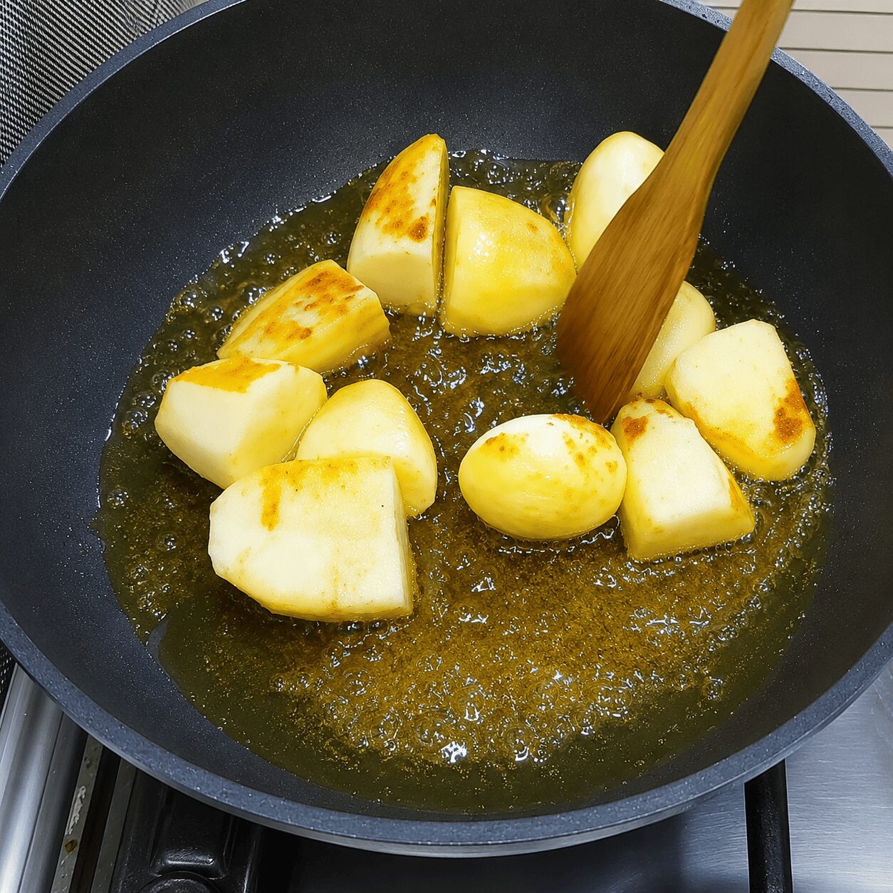 Boiled eggs and potato pieces frying together in mustard oil for Chicken Dark Bunglow