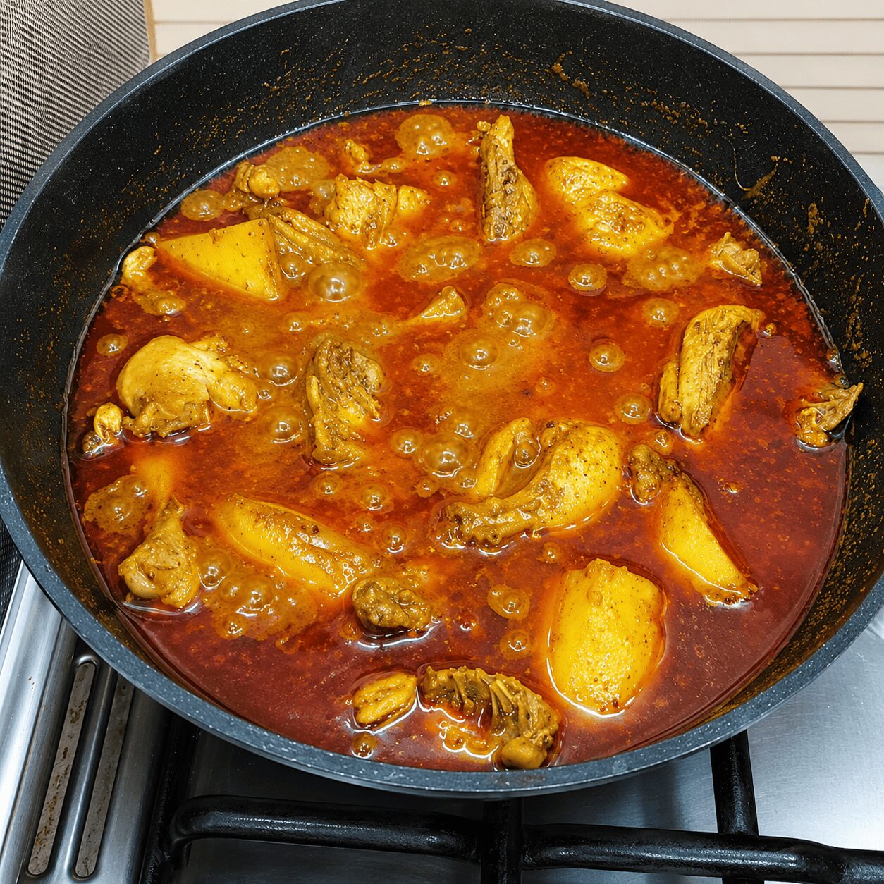 Chicken simmering in the thick spiced gravy for Chicken Dark Bunglow