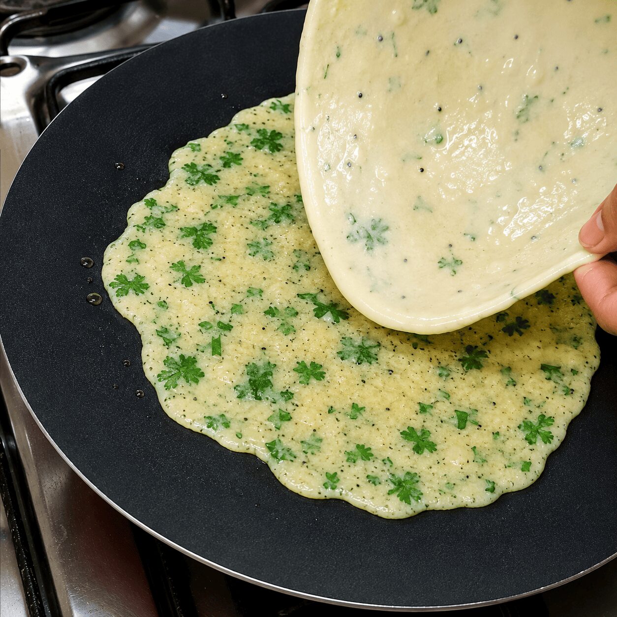 Egg mixture spread on the tawa and paratha pressed into it for Anda Paratha Roll