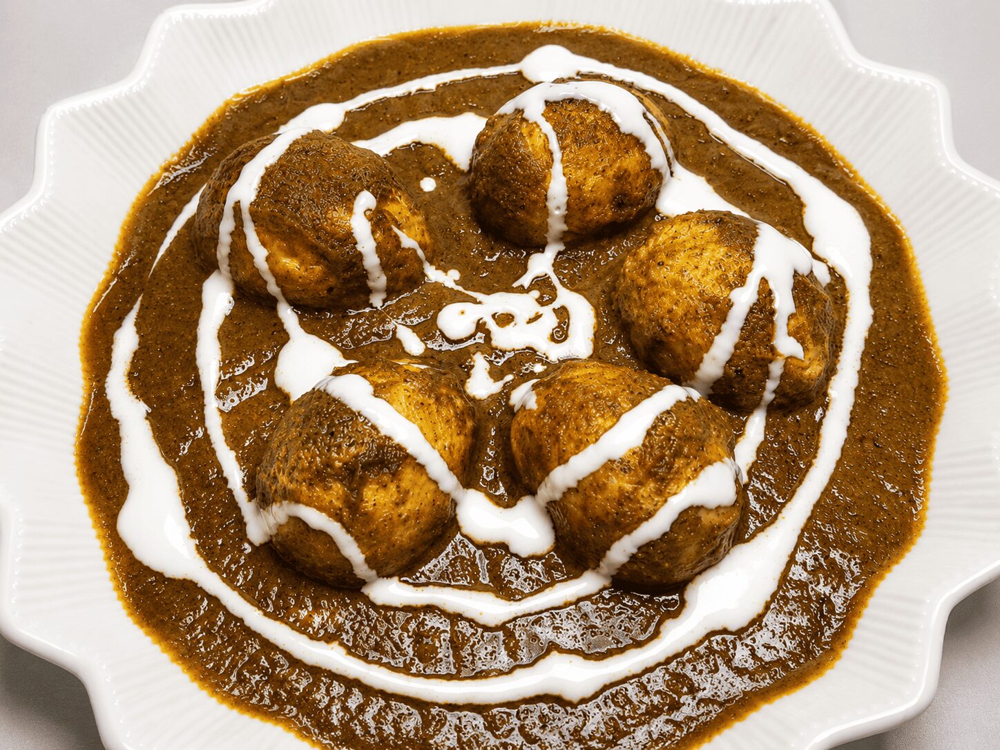 Finished Anda Palak Butter Masala with cream swirl garnish, served with white rice