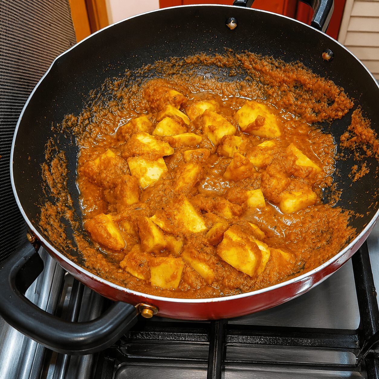 Fried potato cubes simmering in the masala gravy for Anda Aloo Salan