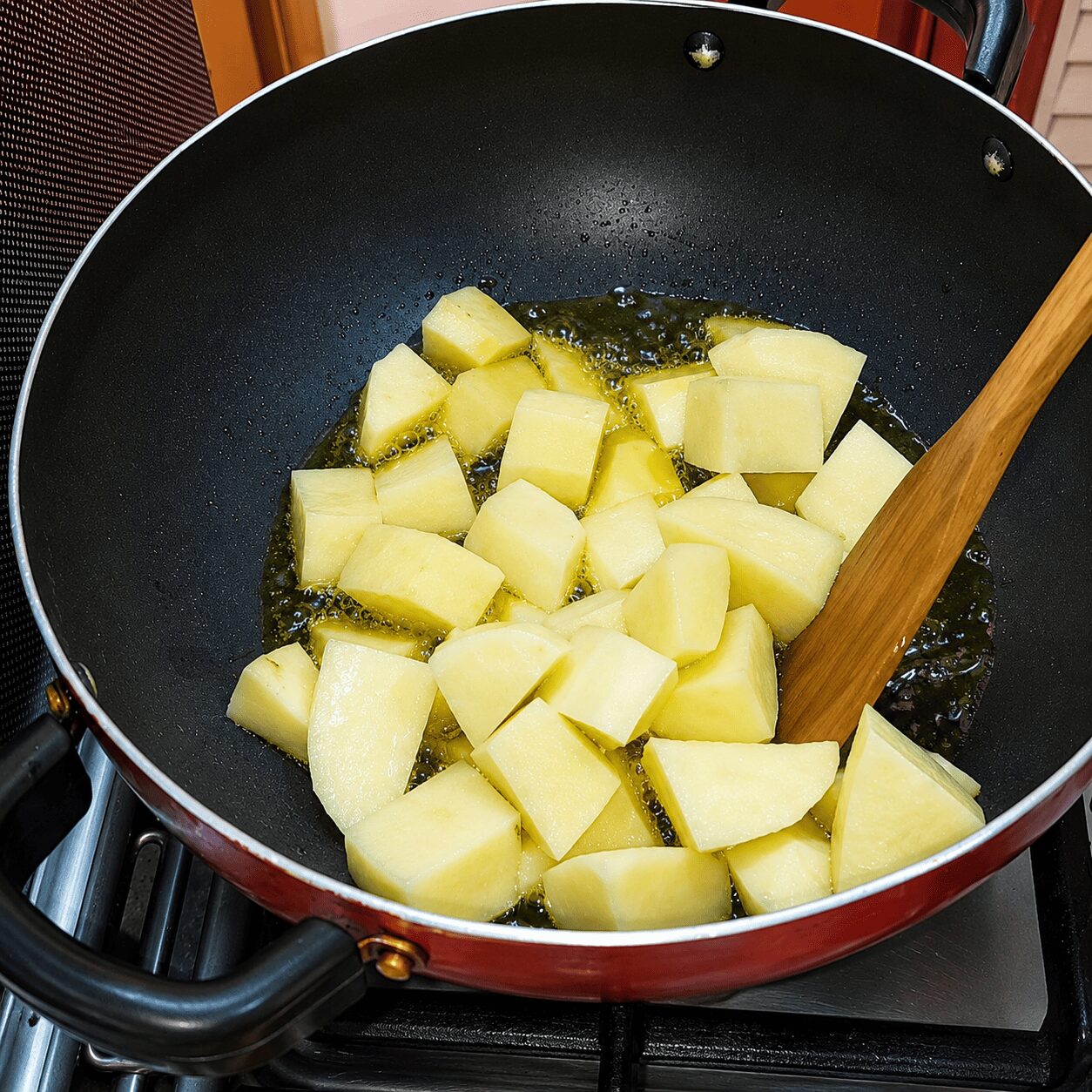 Potato cubes frying to light golden in mustard oil for Anda Aloo Salan