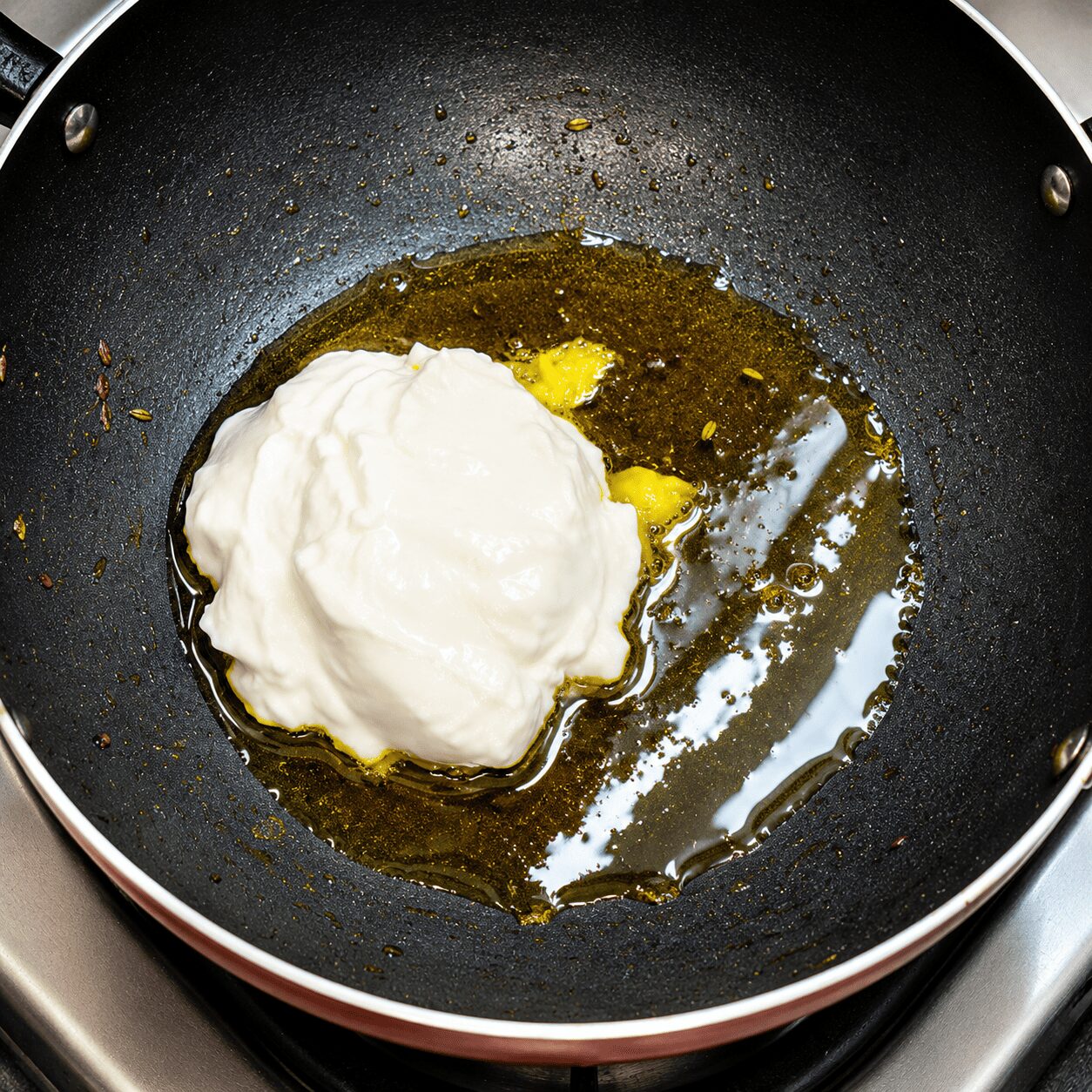 Mixing cold yogurt and spices off the heat before roasting, Anda Korma