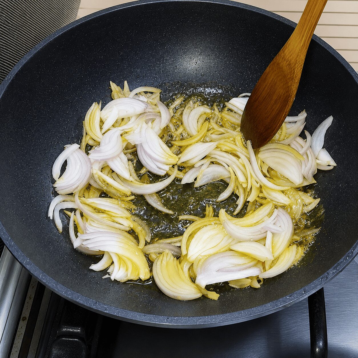 Sliced onions turning golden with green cardamom and cinnamon for Chicken Dark Bunglow