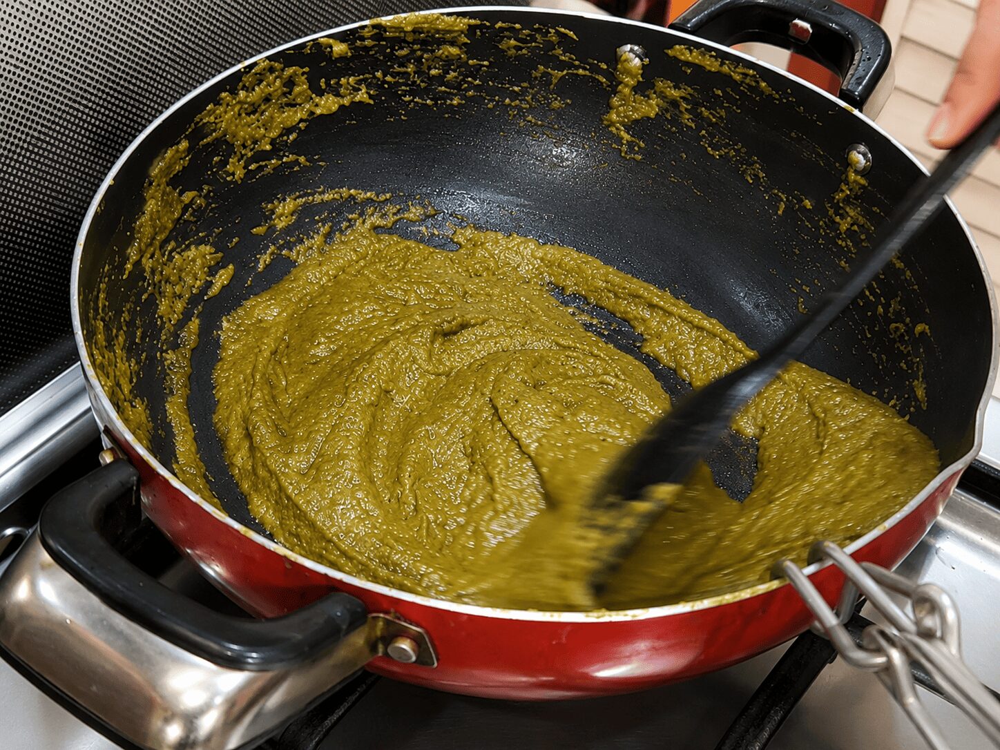Spinach paste roasting with dry spices until oil separates for Anda Palak Butter Masala